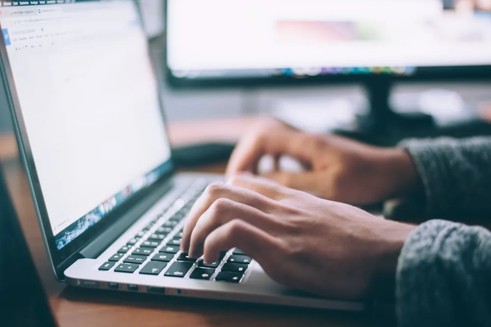 WordPress development: hands typing on a laptop and desktop monitor